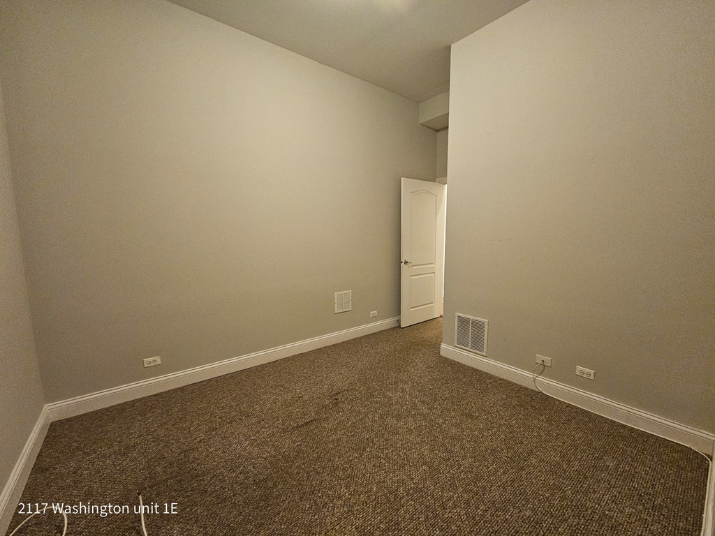 a bedroom with a carpet and a door to a closet