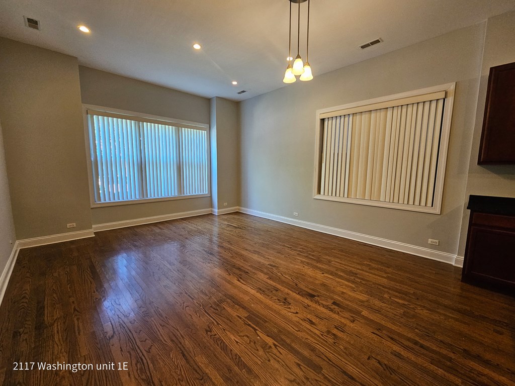 an empty living room with wood floors and a window