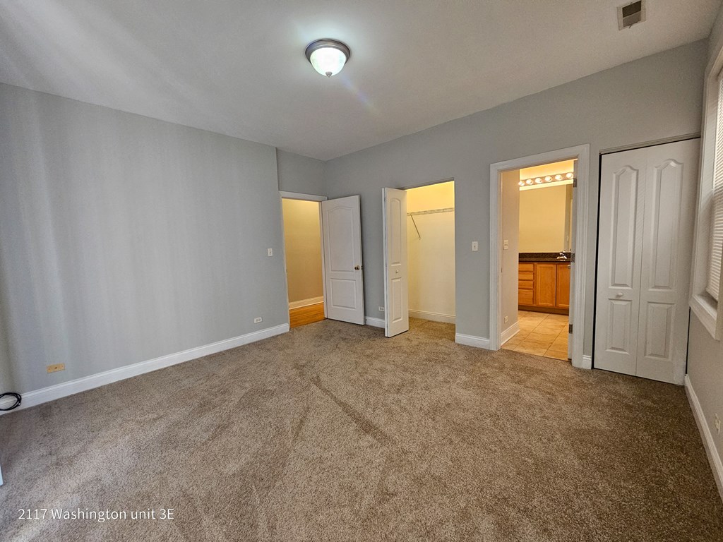 a bedroom with three doors and a carpeted floor
