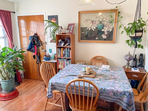 A dining room with a floral tablecloth and wooden chairs.