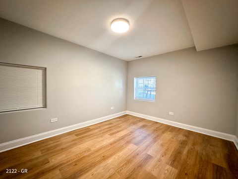A room with wooden flooring and a window with blinds.