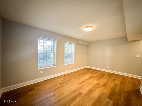 A room with wooden floors and two windows.