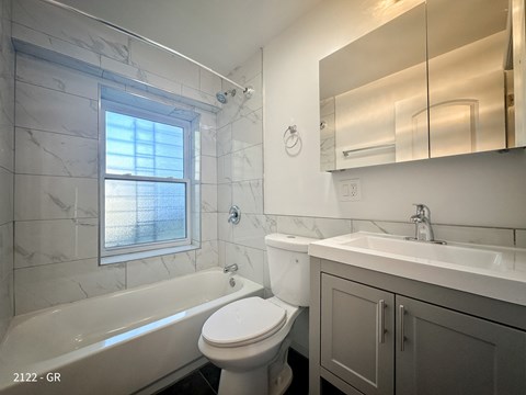 A white toilet sits next to a bathtub in a bathroom.