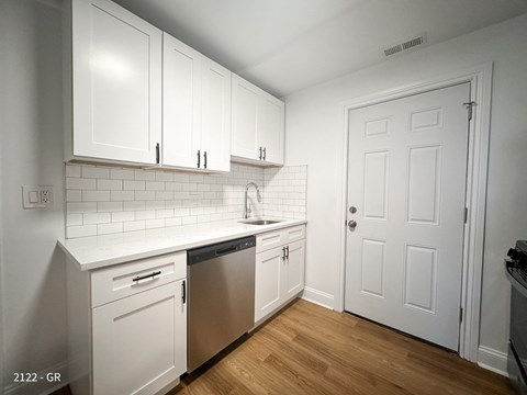 A kitchen with white cabinets and a white door.