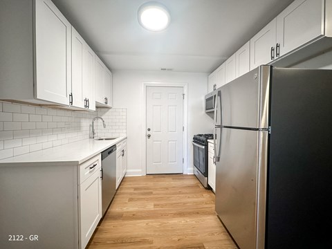 A kitchen with white cabinets and a black refrigerator.