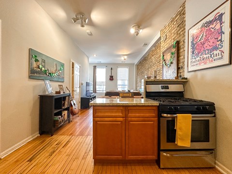 A kitchen with a stove top oven and a wooden floor.