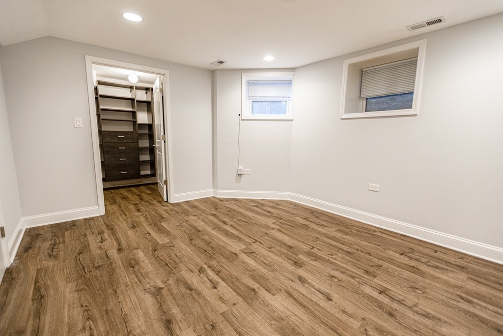 A room with wooden flooring and a window with blinds.
