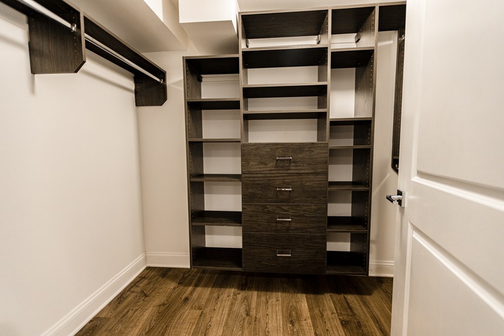 A tall wooden shelving unit with drawers is in a corner of a room.