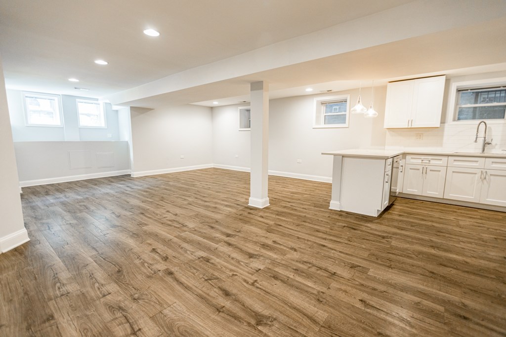 A spacious room with wooden flooring and white cabinetry.
