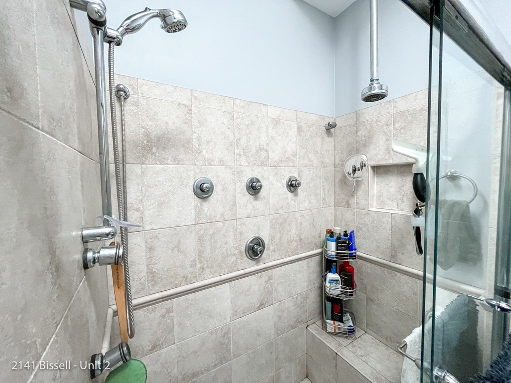 a walk in shower with tiled walls and a glass door