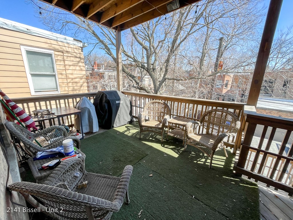 a deck with wicker chairs and a grill