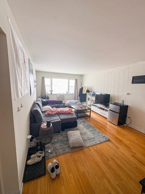 A living room with a grey couch, a television, and a window with curtains.