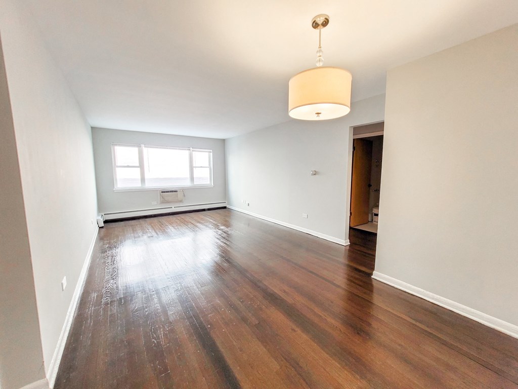 an empty living room with wood flooring and a window