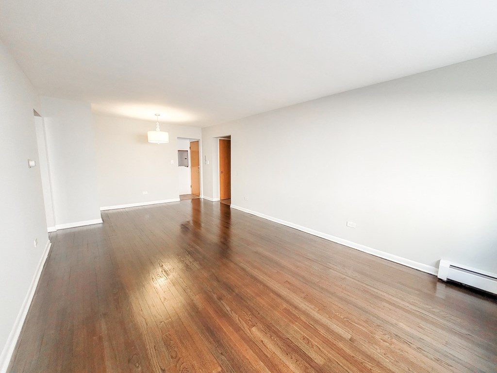 an empty living room with wood floors and white walls