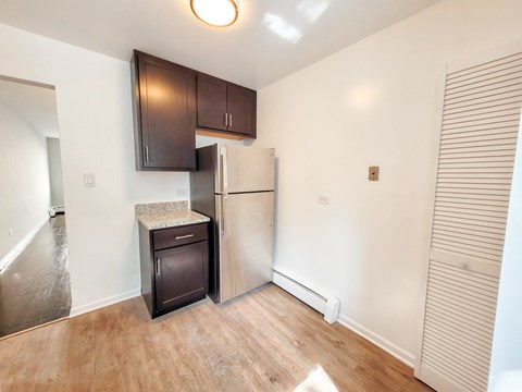 A kitchen with a refrigerator, microwave, and cabinets.