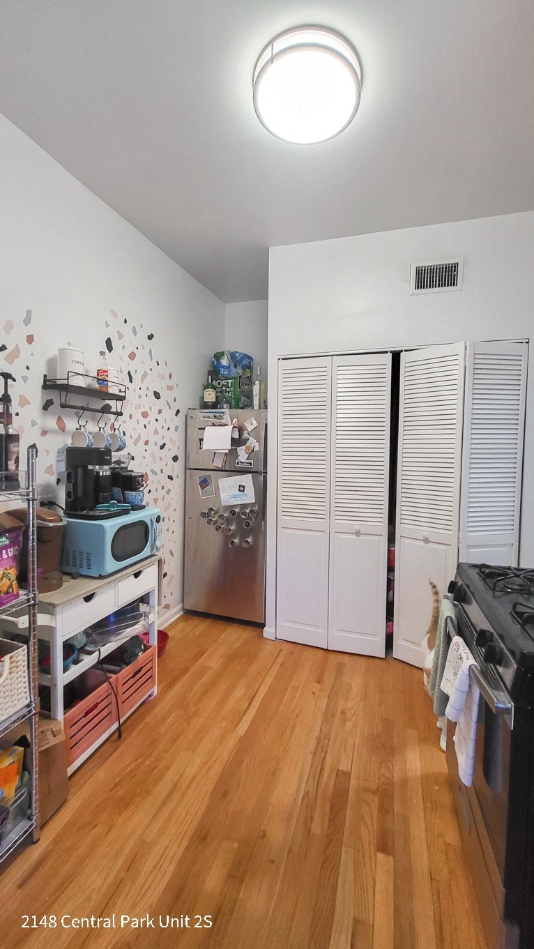 a kitchen with wooden floors and white walls and a refrigerator