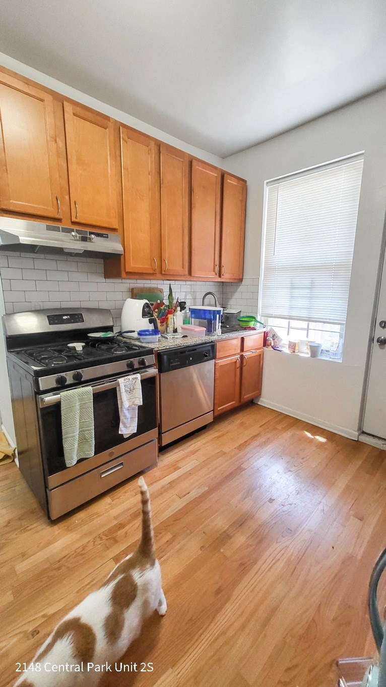 a cat walking in a kitchen with wooden flooring