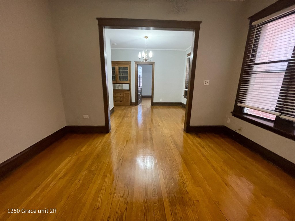 an empty living room with wooden floors and a large window