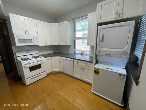 a kitchen with white cabinets and appliances and a wooden floor