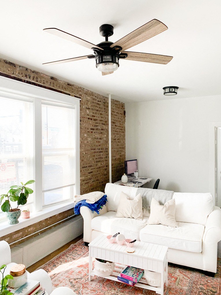 a living room with a white couch and a ceiling fan