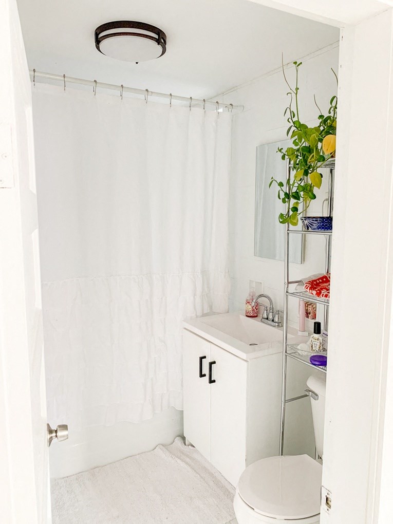 a white bathroom with a white shower curtain and a toilet