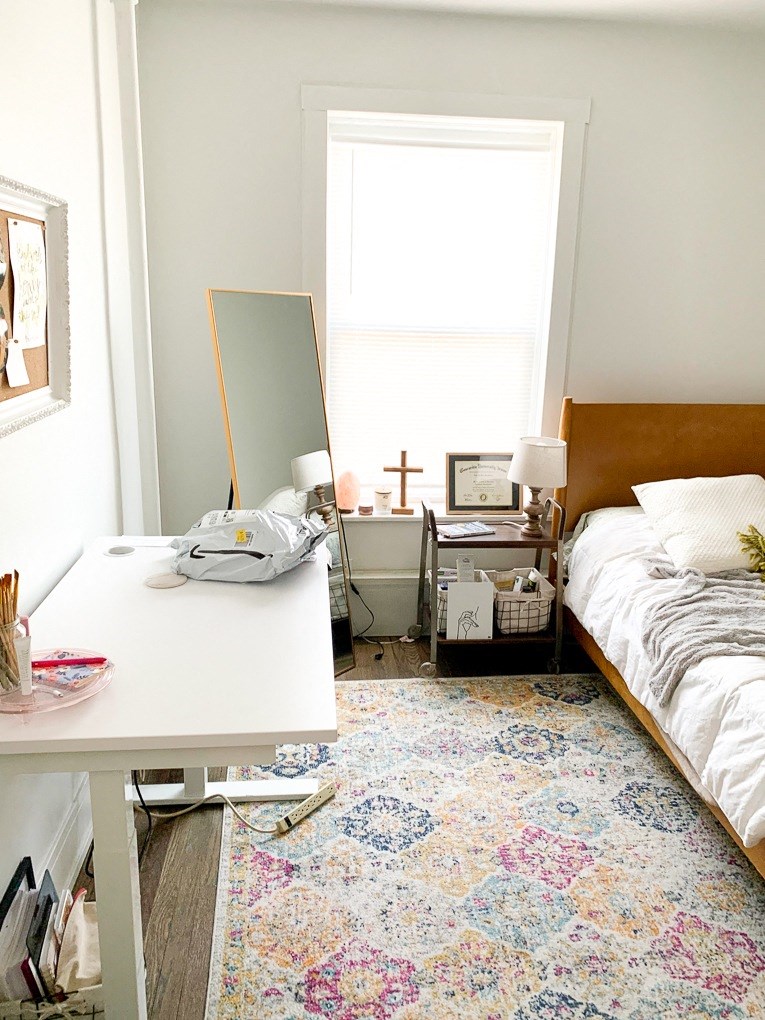 a small bedroom with a bed and a desk and a mirror