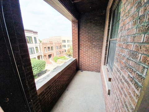 A balcony with a brick wall and a window.