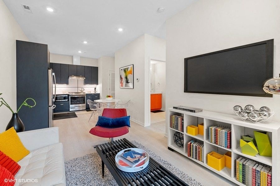 a living room with a tv and a kitchen in the background