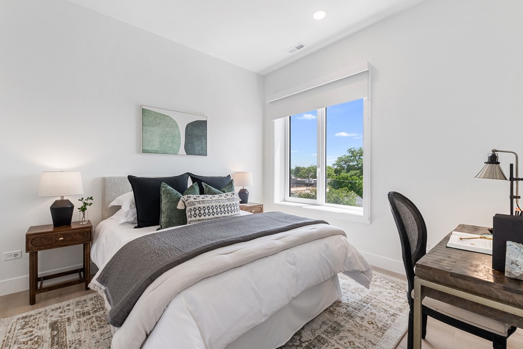 A bedroom with a large bed and a window overlooking a green landscape.