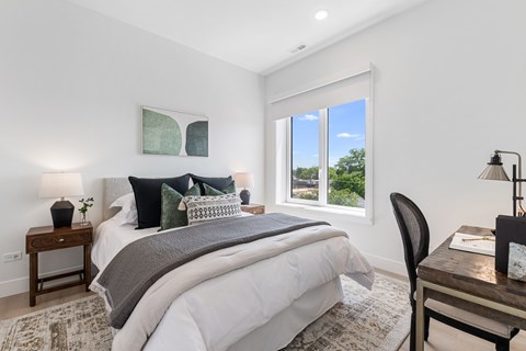 A bedroom with a large bed and a window overlooking a green landscape.