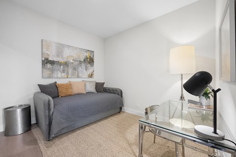 A grey couch with a glass table in front of it.