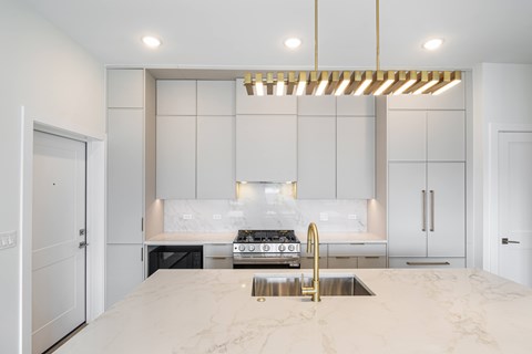 A modern kitchen with a marble countertop and a stove top oven.