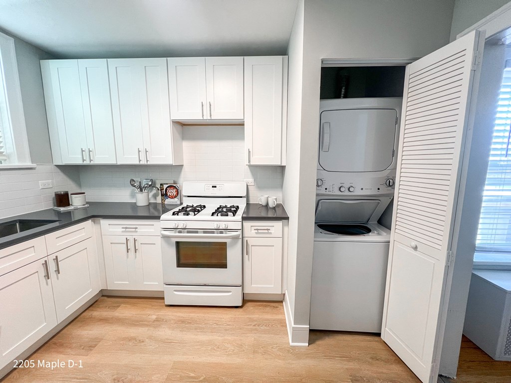 A kitchen with a white stove and white cabinets.