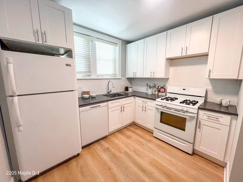 A kitchen with white appliances and wooden floors.