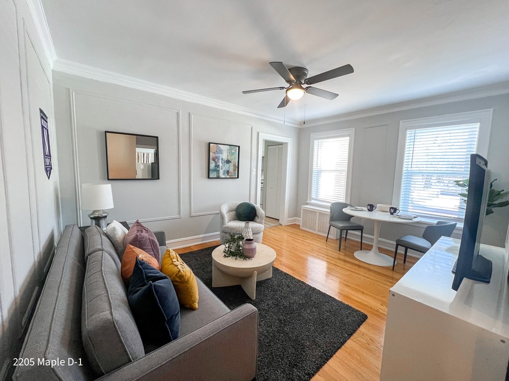 A living room with a grey couch and a ceiling fan.