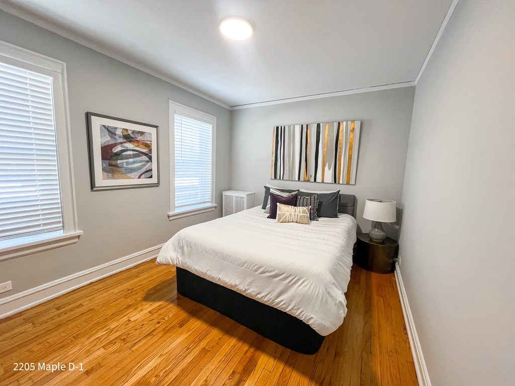 A bedroom with a bed, nightstand, and a painting on the wall.