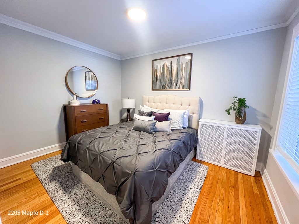 A bedroom with a bed, nightstand, and a painting on the wall.