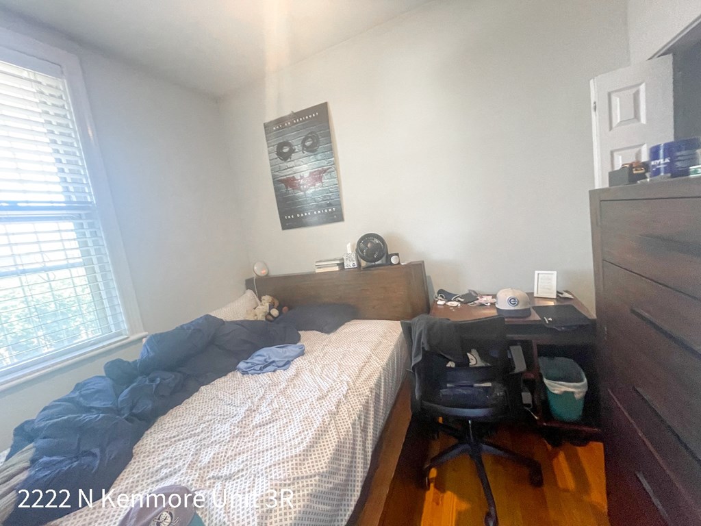 a bedroom with a bed and a desk and a window