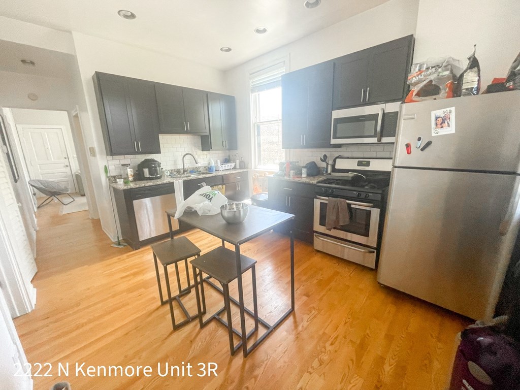 an empty kitchen with stainless steel appliances and a table