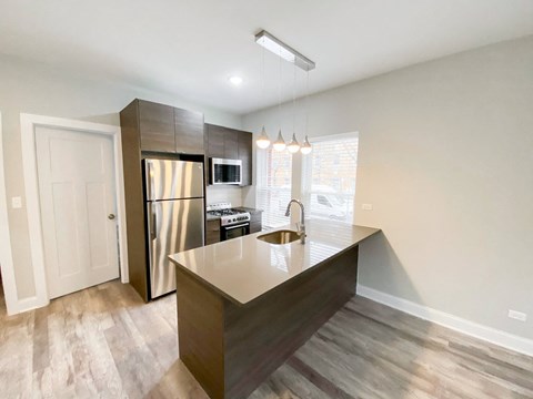 a kitchen with a large island and stainless steel refrigerator