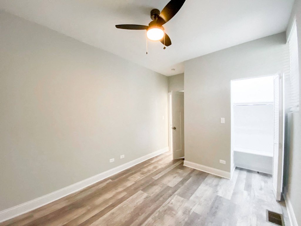 an empty living room with a ceiling fan and wood floors