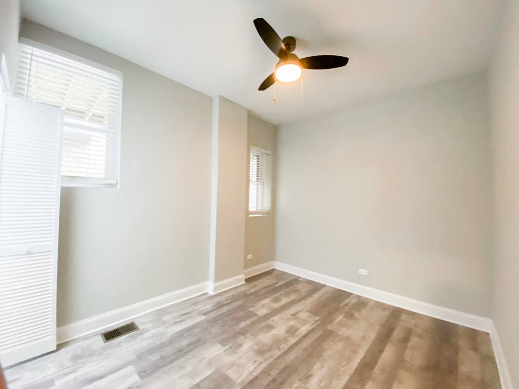 an empty living room with a ceiling fan and a window
