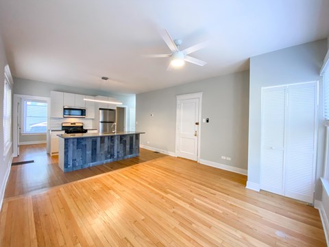 A spacious room with wooden floors and a ceiling fan.