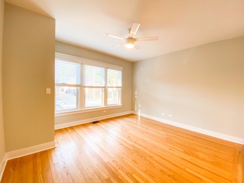 A room with a ceiling fan and wooden flooring.