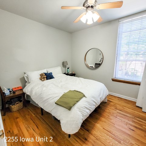 A bedroom with a white bed and a ceiling fan.