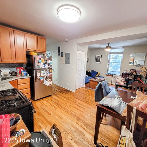A kitchen with a refrigerator, stove, and wooden floors.