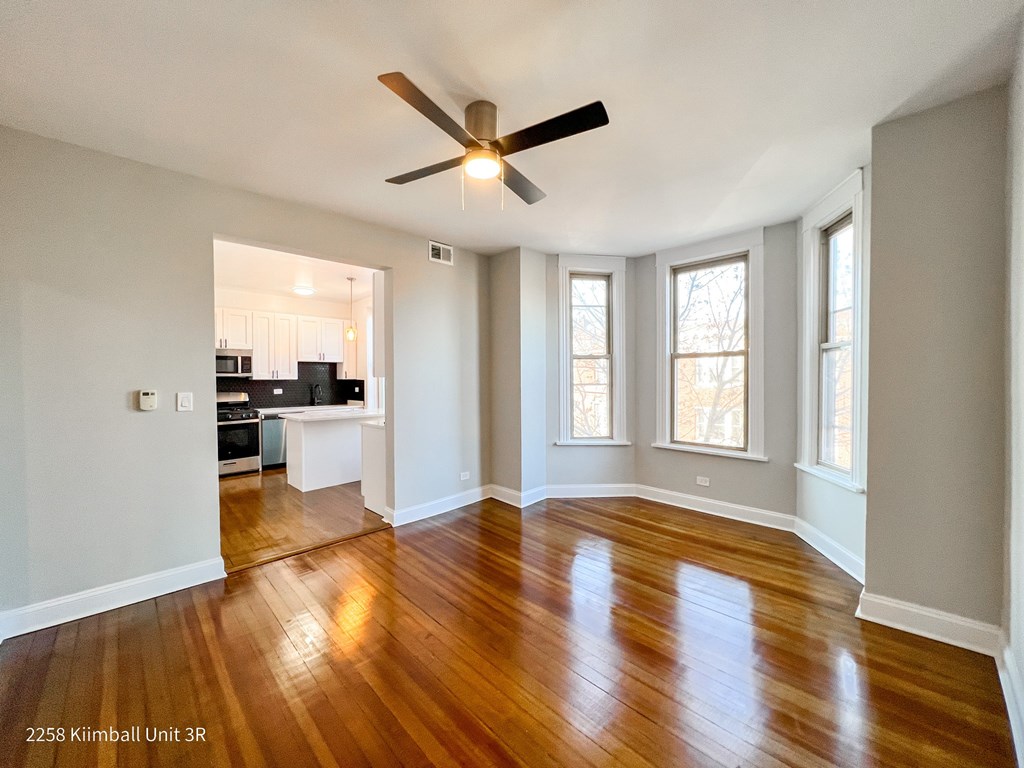 A spacious room with a ceiling fan and wooden flooring.