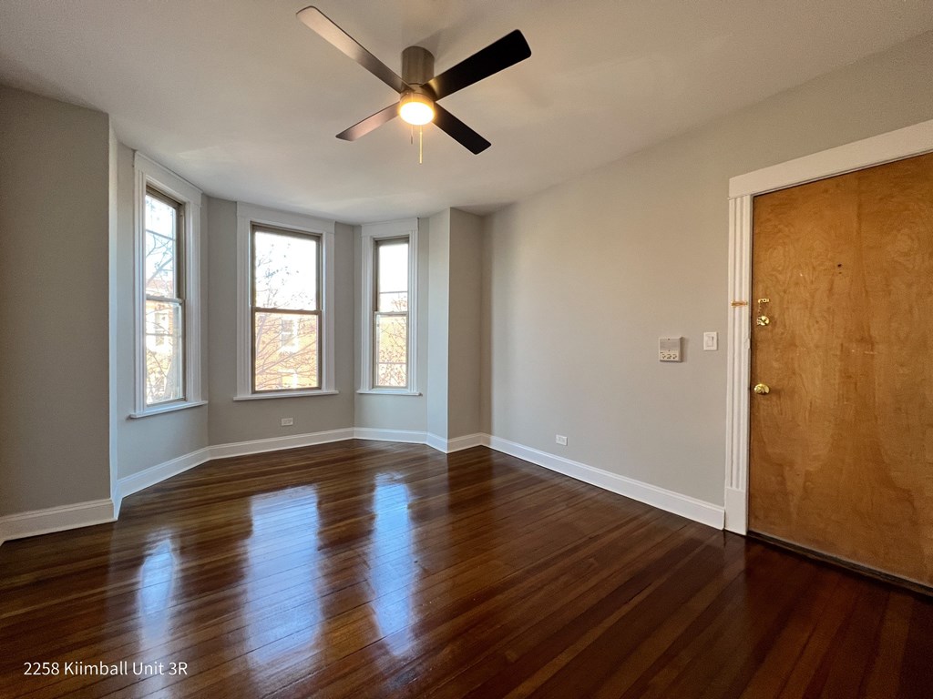 A room with a ceiling fan and wooden floors.