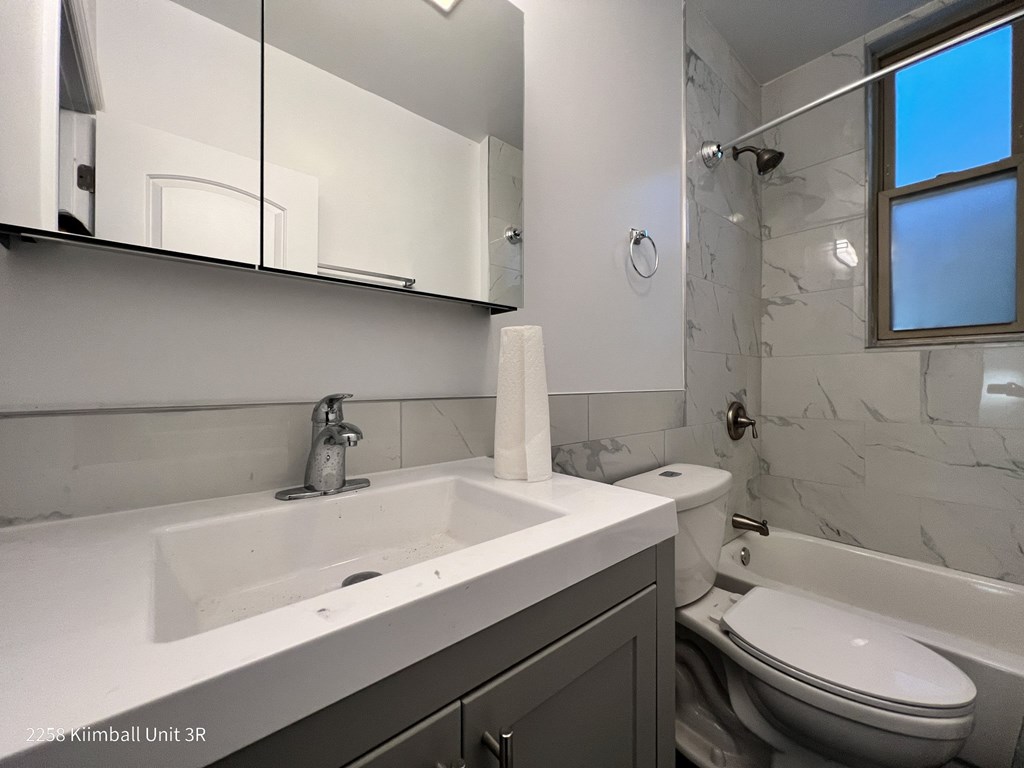 A white sink with a silver faucet and a toilet in a bathroom.