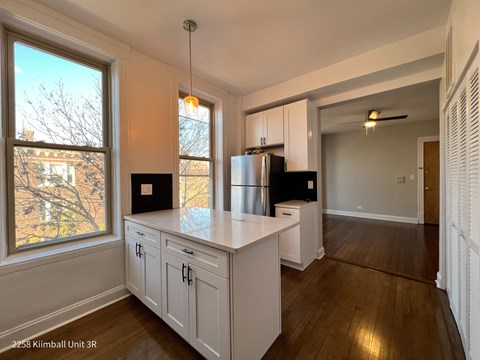 A kitchen with white cabinets and a black fridge.